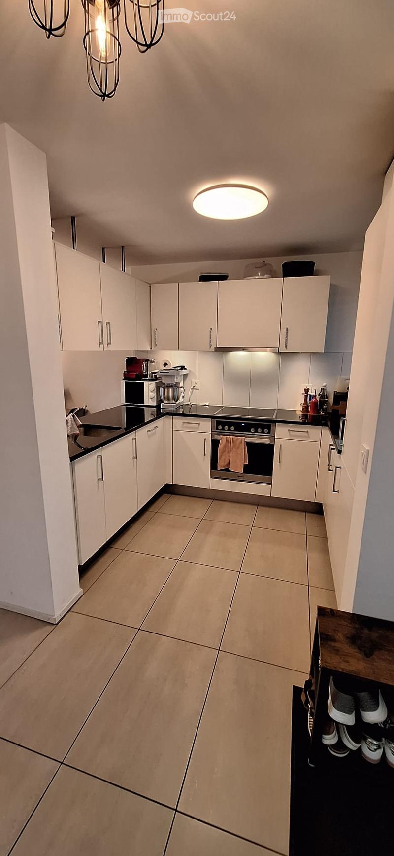 Modern kitchen with white cabinets, stainless steel appliances, and a black countertop. Features include a built-in oven, sink, and various small appliances.
