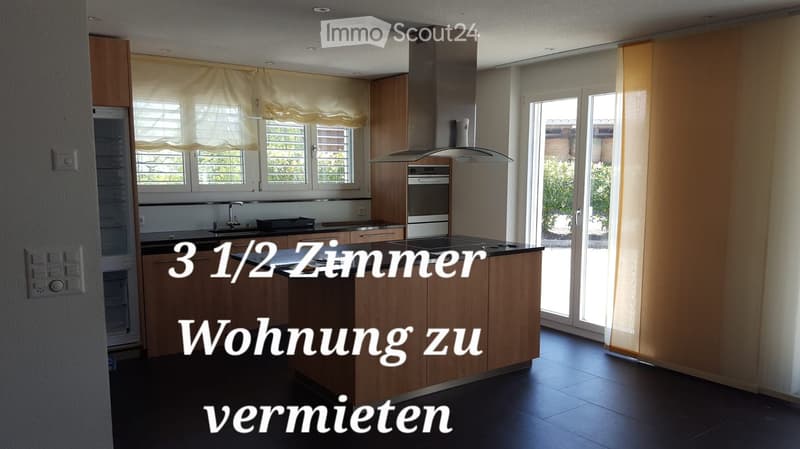 Modern kitchen with wooden cabinets, stainless steel appliances, island, and large windows with blinds.