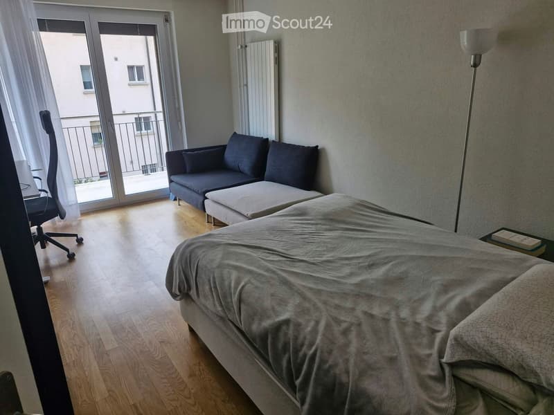 Modern bedroom with a large bed, sofa, chair, and a balcony view.