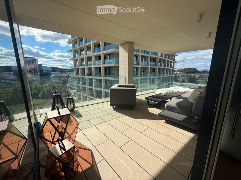 Modern balcony with a sofa, coffee table, chairs, and lamps, offering a panoramic city view.
