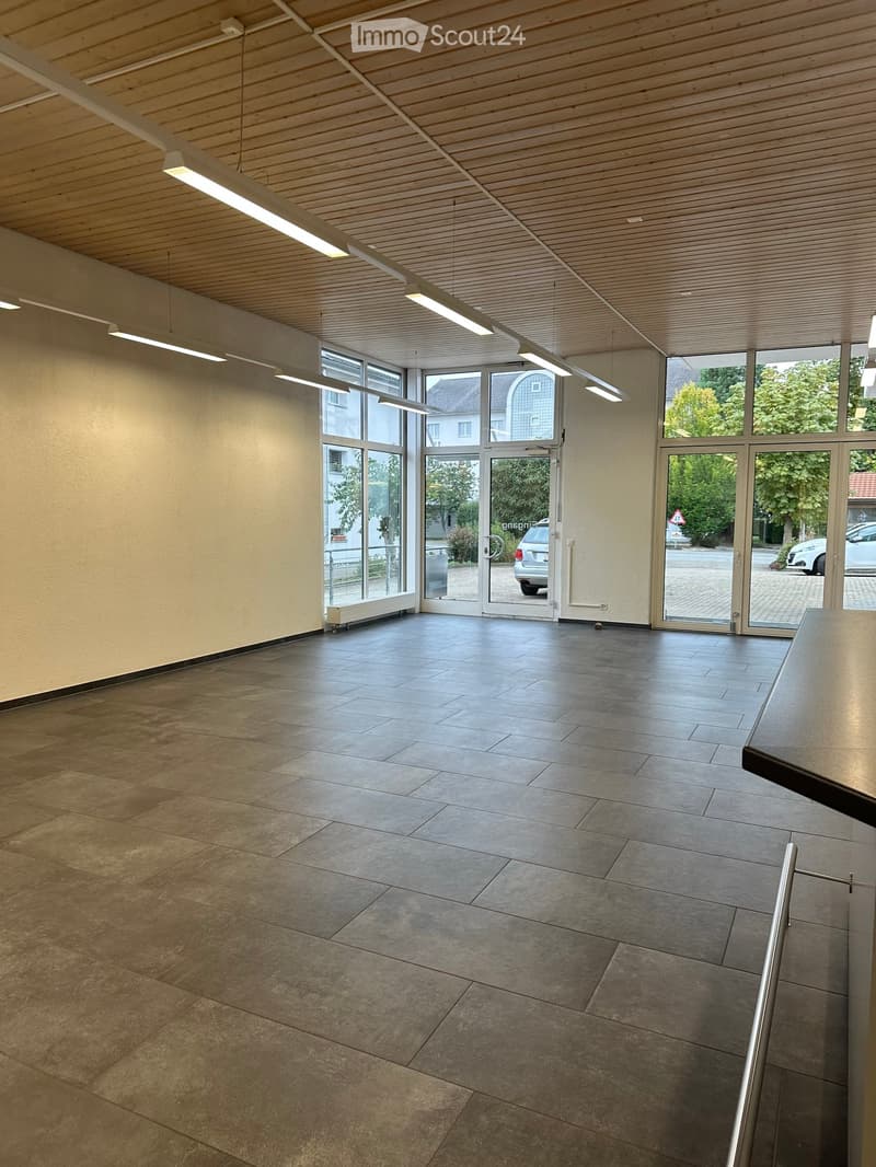 Empty room with tiled floor, large windows, and a door leading outside. No furniture or equipment present.