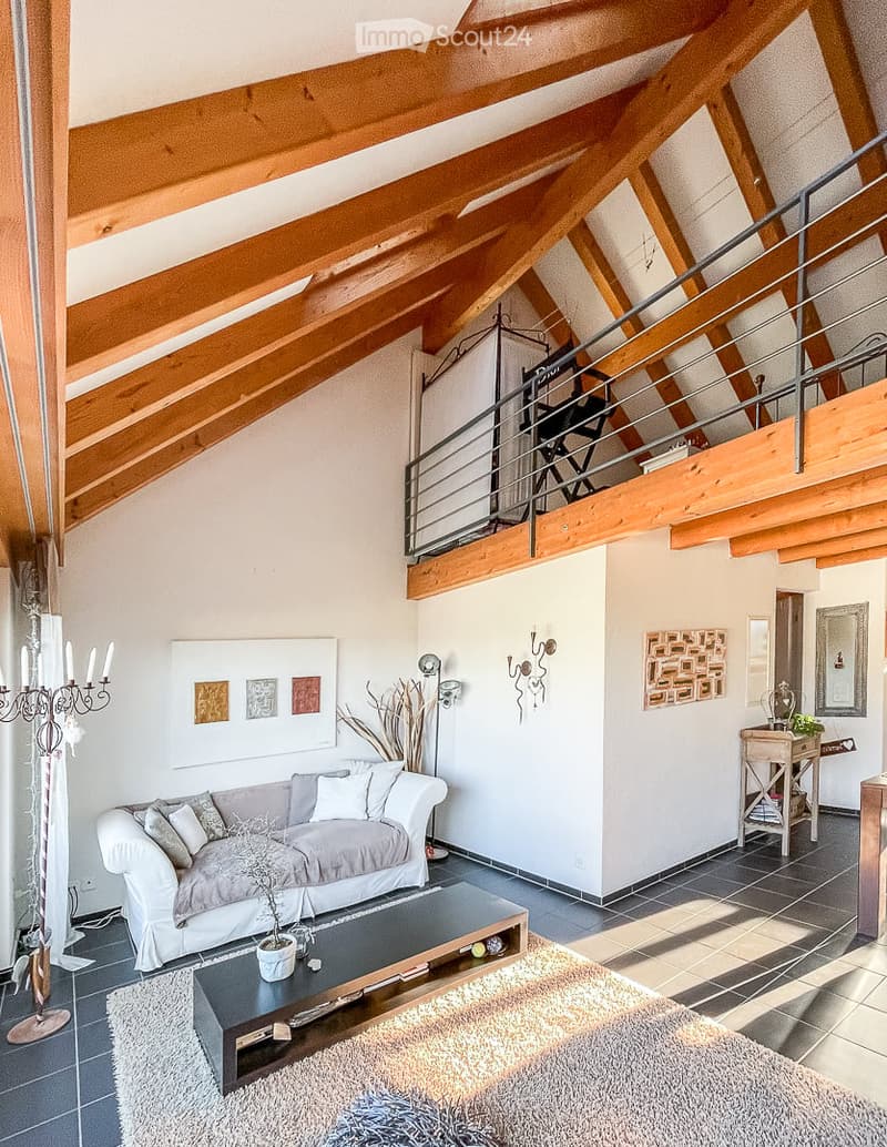 Living room with exposed wooden beams, a grey sofa, coffee table, floor lamp, side table, and decorative artwork.