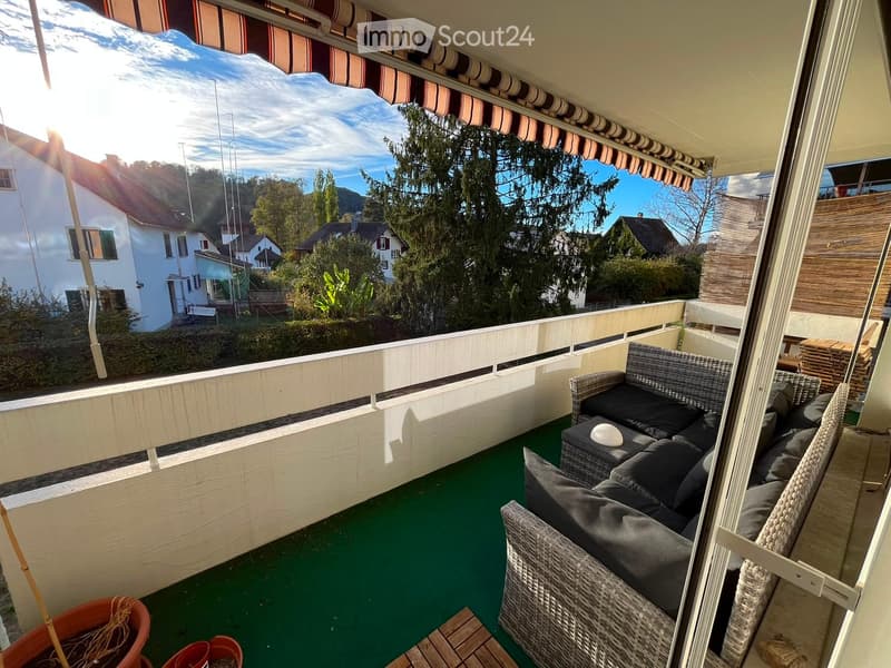 Balcony with green flooring, white railing, and outdoor furniture including a sofa, chairs, and a table.