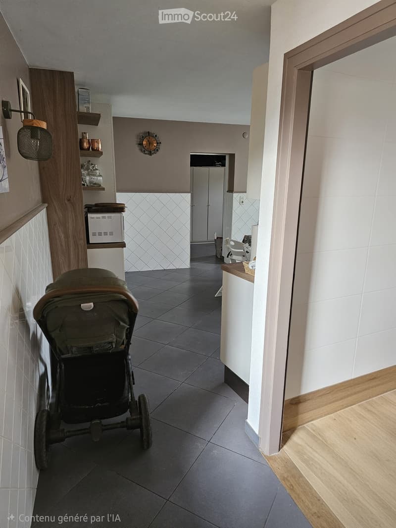 Modern hallway with grey tiled floor, white walls, wooden trim, and a stroller in the foreground. Shelves with decorative items and a small room visible at the end.