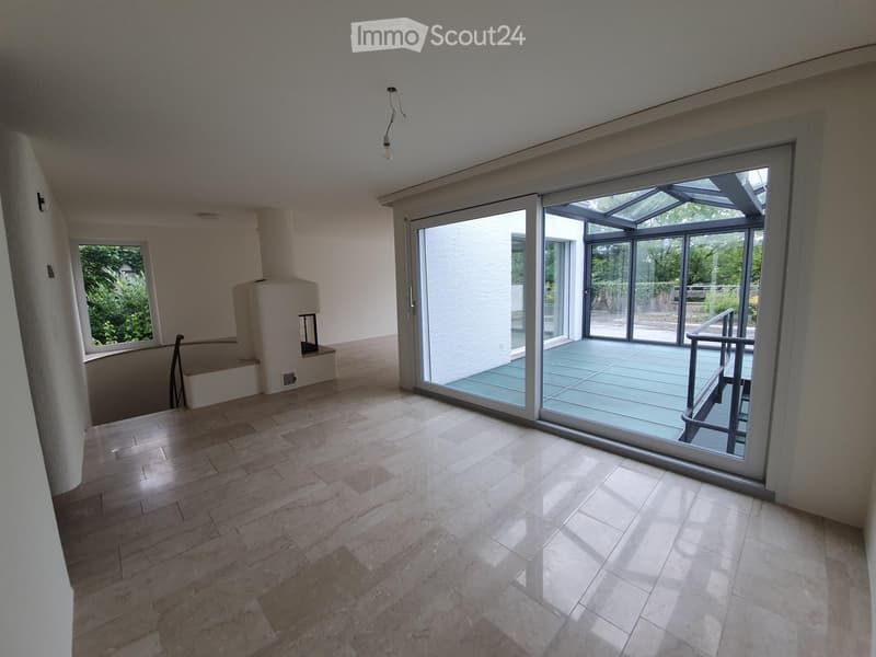 Empty room with wooden flooring, large sliding glass doors leading to a balcony, and a fireplace on the left side.