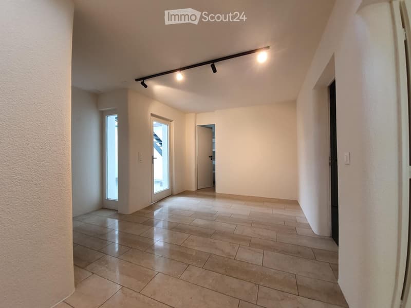 Empty hallway with tiled floor, white walls, and recessed lighting. Features a door and a window allowing natural light.