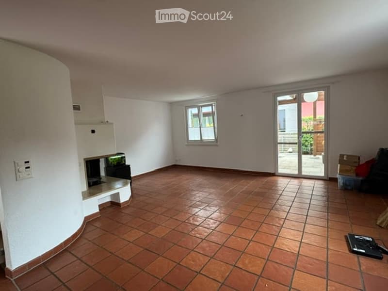 Empty room with tiled floor, white walls, a fireplace, and a sliding glass door leading to a balcony.