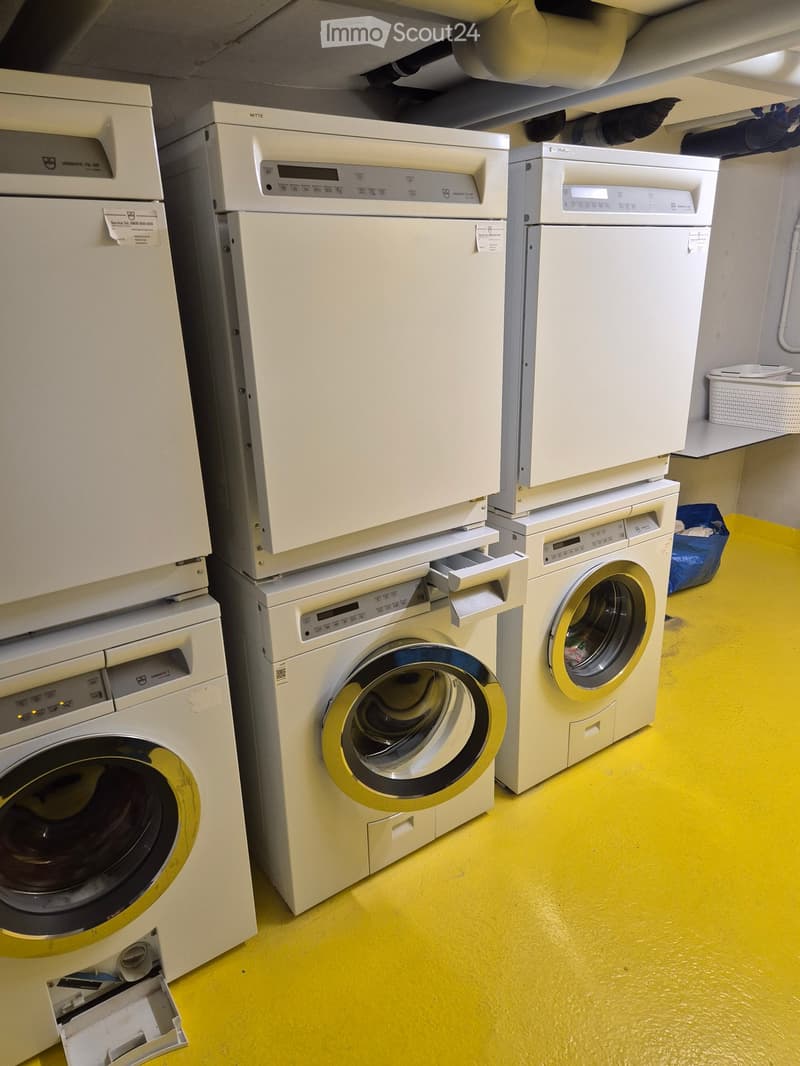 A room with multiple stacked washing machines and dishwashers, yellow flooring, and white walls.