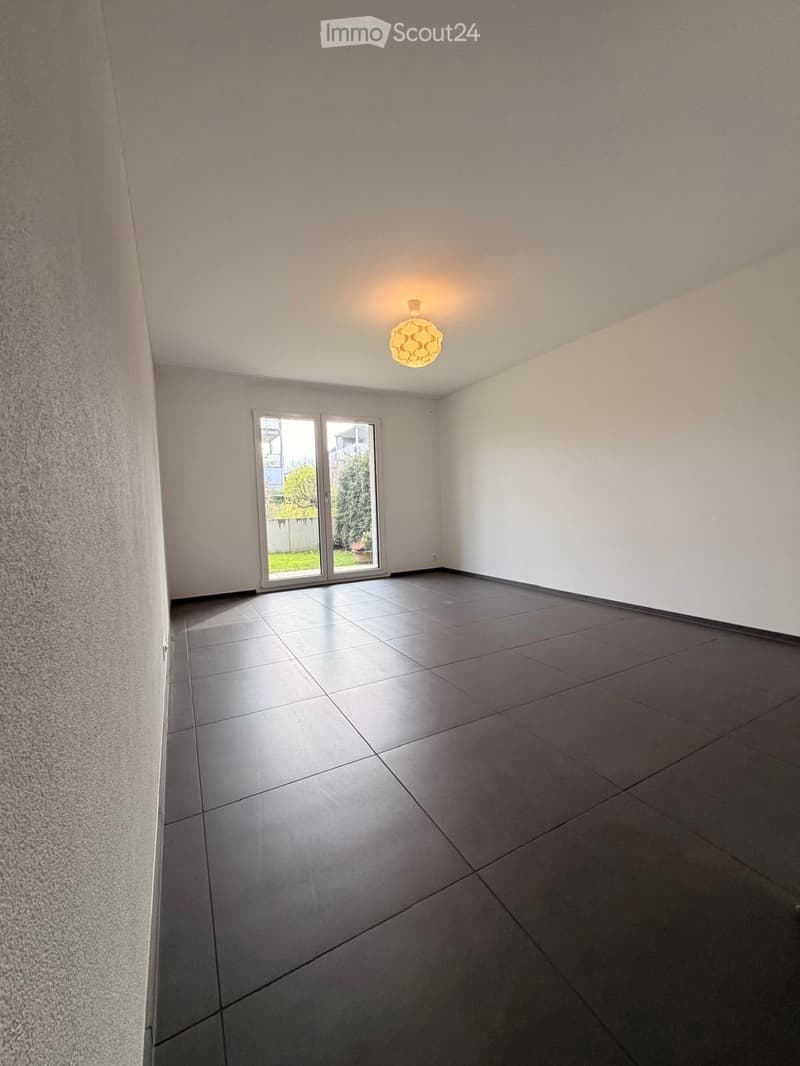 Empty room with tiled floor, white walls, and a large sliding glass door leading to an outdoor area.
