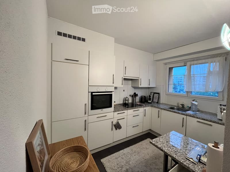 Modern kitchen with white cabinets, granite countertops, and stainless steel appliances. Features include an oven, sink, and various kitchen items on the counter.