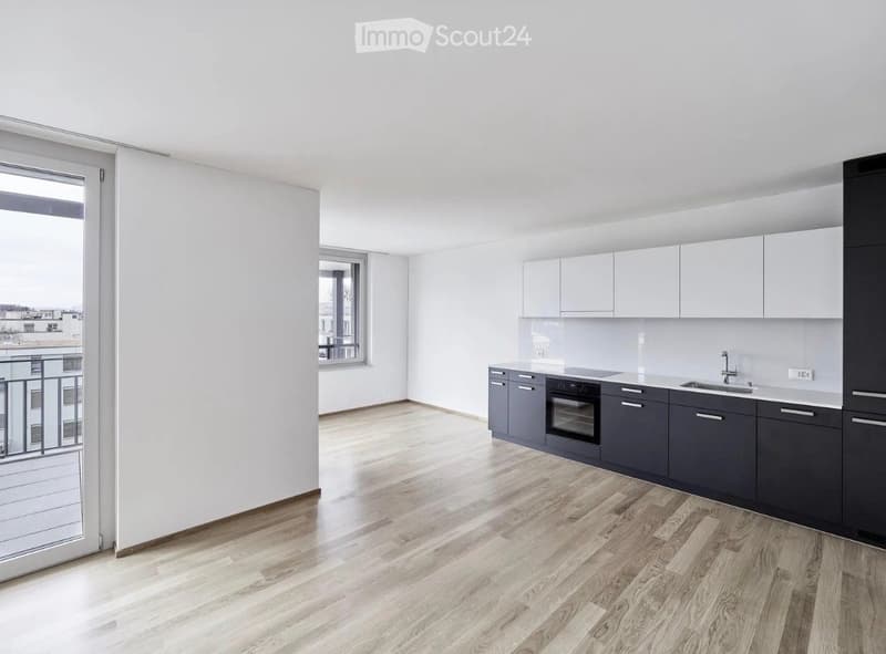 Modern kitchen with light grey cabinets, dark grey lower units, a sink, and an oven. The space features wooden flooring and large windows with a balcony view.