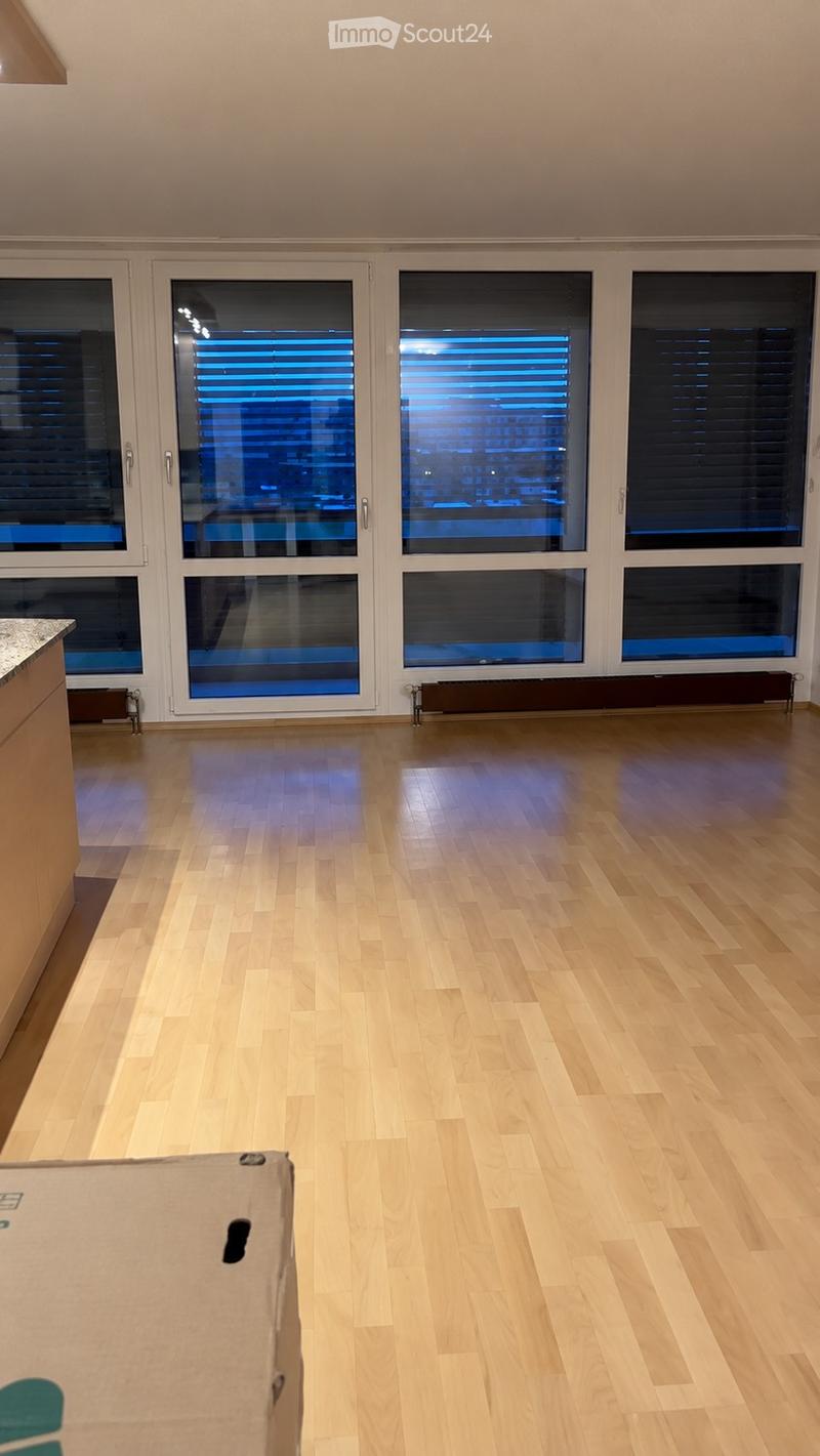 Empty room with wooden flooring, large windows with blinds, and a radiator under the windows.