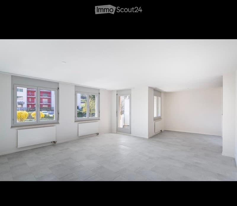 Empty room with white walls, tiled floor, large windows, and radiators. No furniture or equipment present.