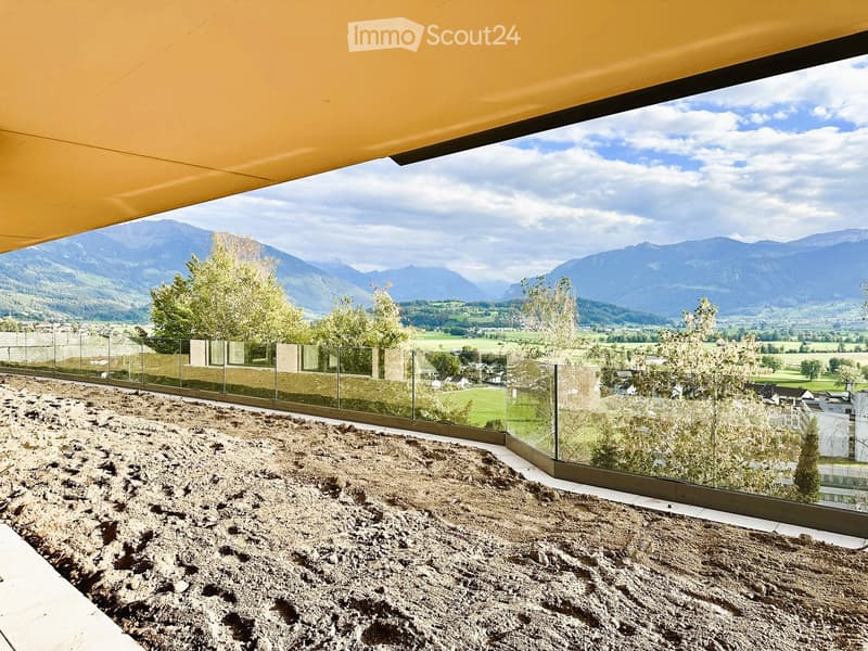 Balcony with glass railing, gravel surface, and scenic mountain view.