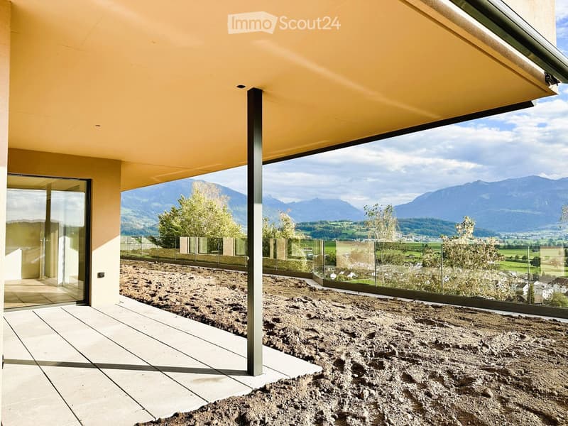 Modern balcony with large glass windows offering a scenic mountain view, tiled floor, and a partially covered roof.