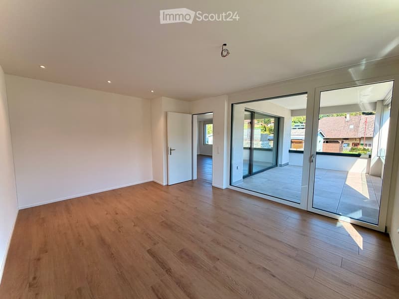 Empty room with wooden flooring, white walls, and large sliding glass doors leading to a balcony.