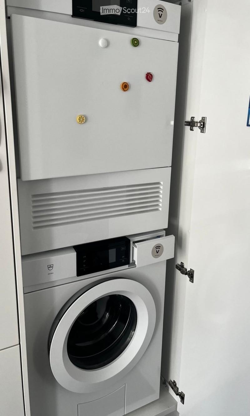 Modern bathroom with a white washing machine and a dishwasher stacked vertically, featuring sleek control panels and a clean, minimalist design.