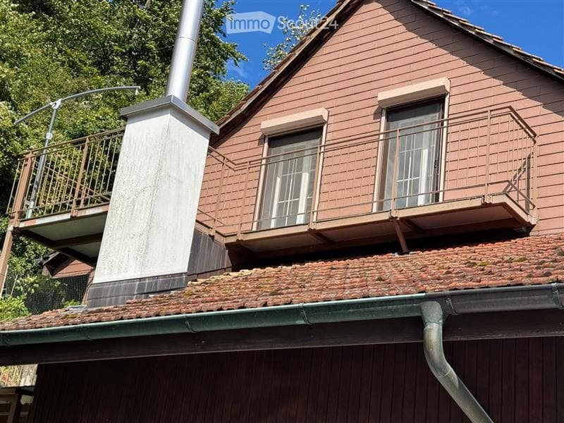 chimney, terrace with iron railing, two windows