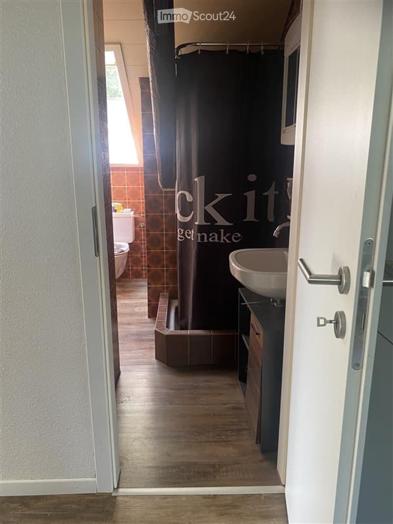 Tiled floor, white sink, brown shower curtain, white toilet