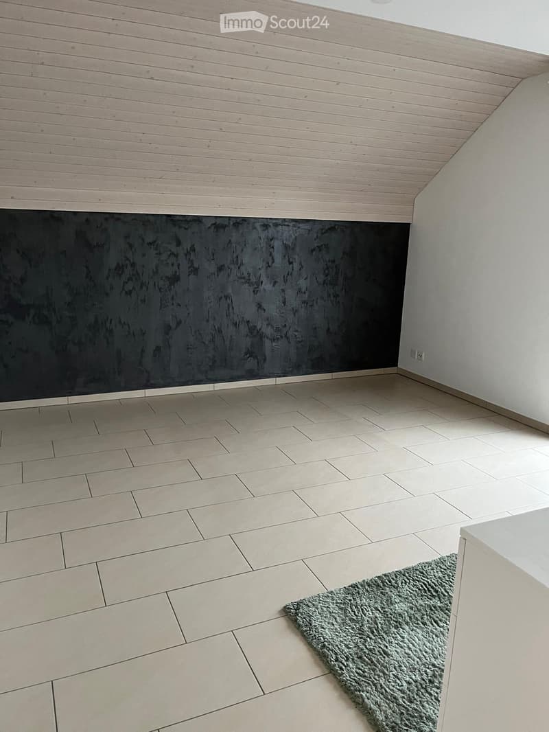 Empty room with tiled floor, light-colored walls, and a small green rug in the corner.