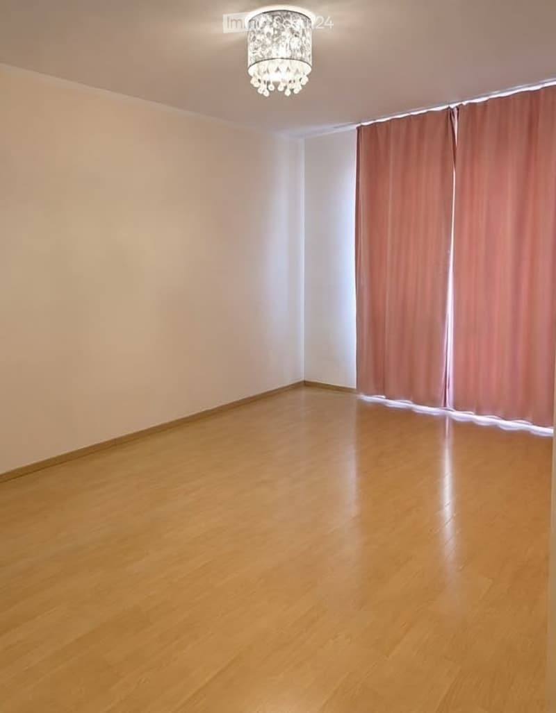 Empty room with wooden flooring, light-colored walls, and a decorative ceiling light fixture.