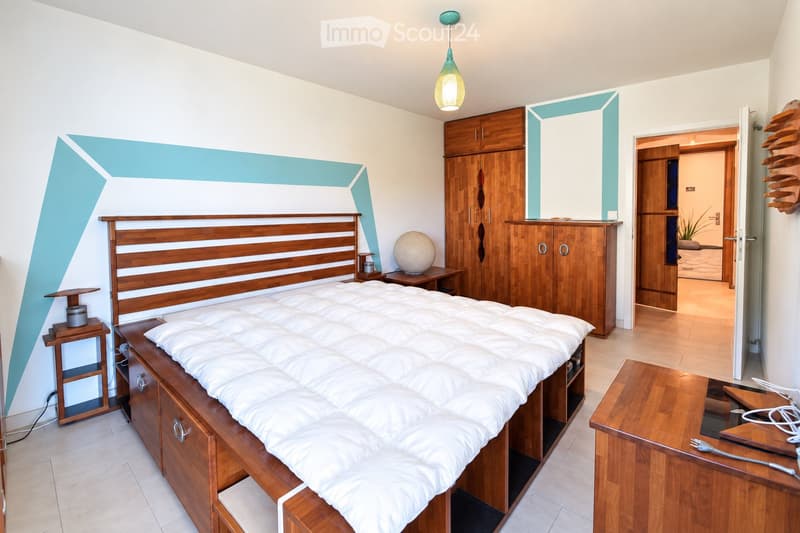Modern bedroom with a large wooden bed, white bedding, nightstands, a round decorative ball, and wooden cabinets.