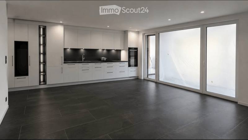 Modern kitchen with white cabinets, black countertops, and large glass sliding doors leading to an outdoor area.