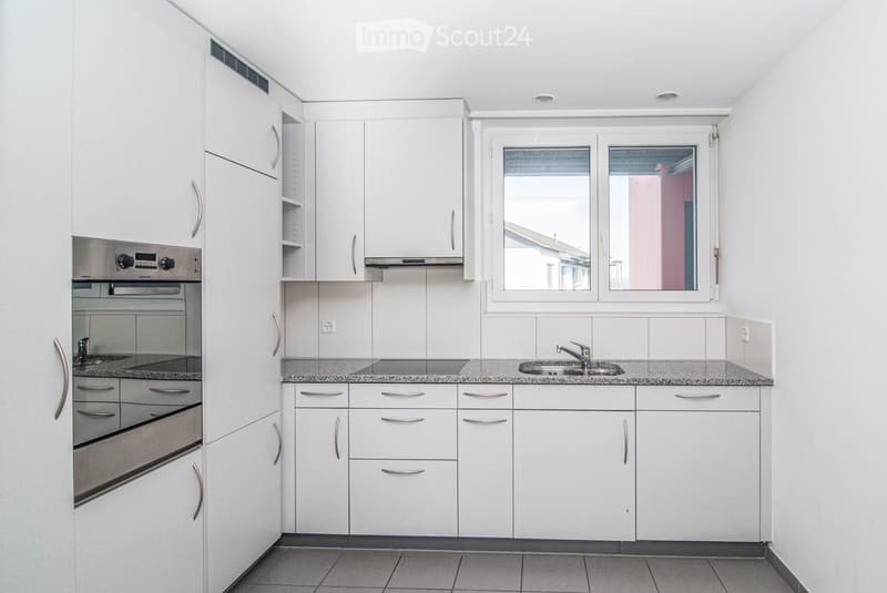 Modern kitchen with white cabinets, stainless steel appliances, and a granite countertop.