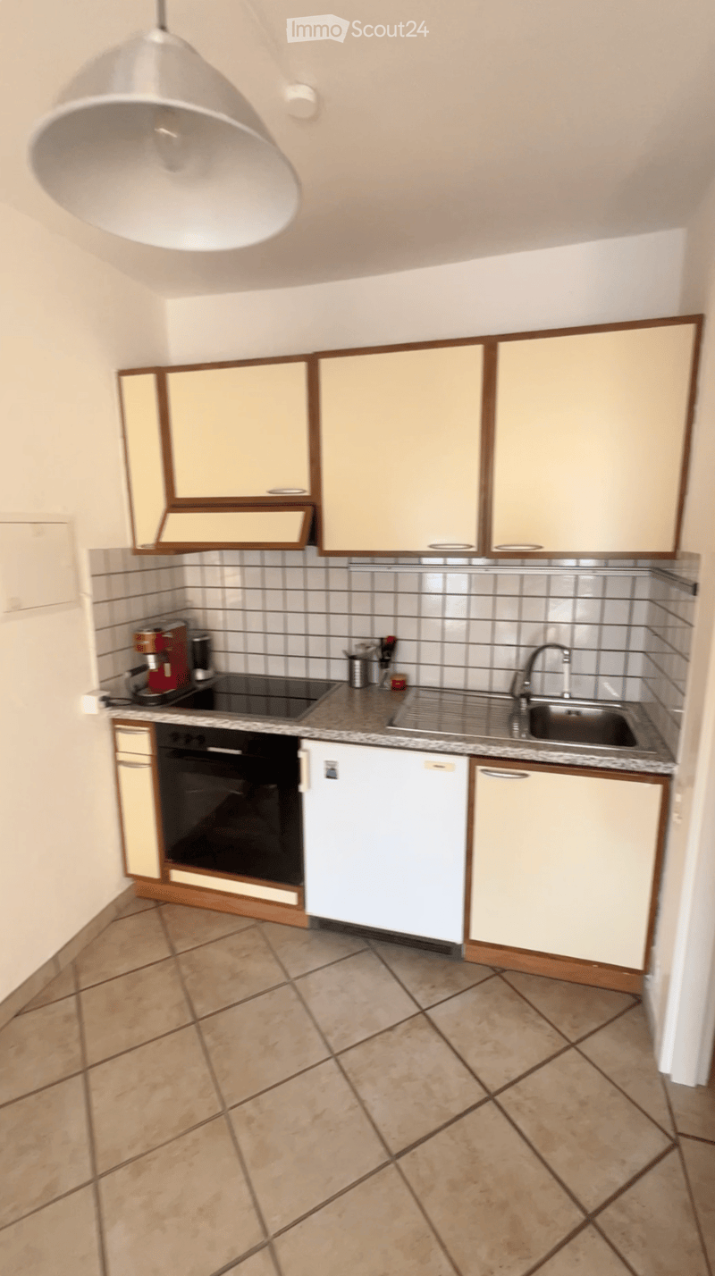 Modern kitchen with light-colored cabinets, tiled backsplash, granite countertop, and stainless steel sink and faucet.