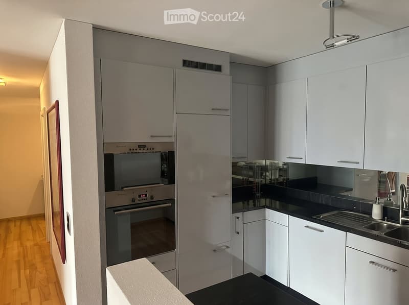Modern kitchen with white cabinets, stainless steel appliances, and a black countertop.
