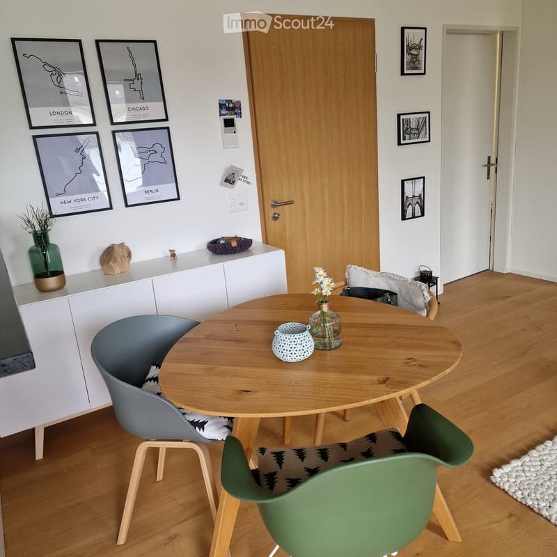 Wooden dining table, 3 chairs, white cabinet, pictures on the wall, wooden floor