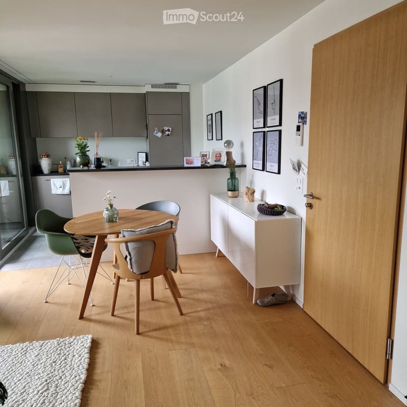 small dining room with 4 chairs, small round wooden table, open kitchen with countertops