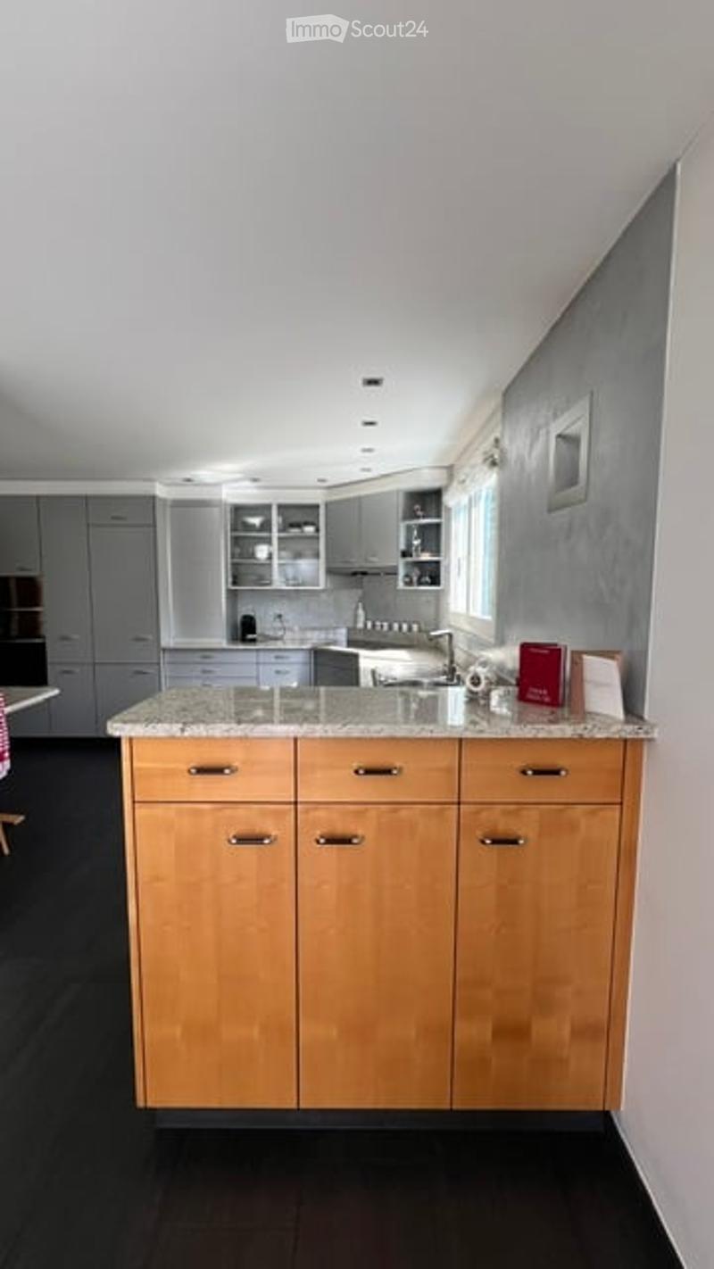 Modern kitchen with grey and wooden cabinets, granite countertop, stainless steel appliances, and a large window.