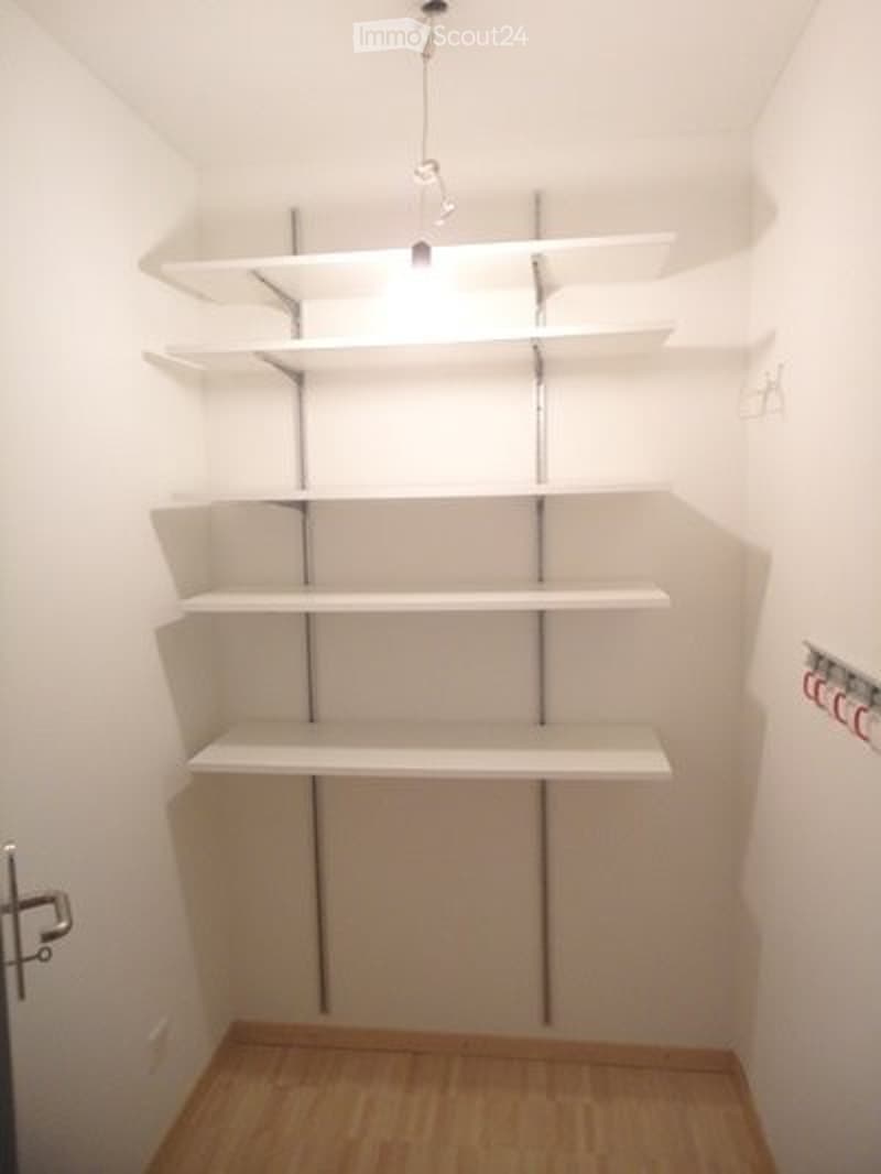 Empty room with white walls, wooden floor, and built-in white shelves with metal supports.