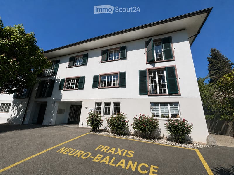 Two-story white building with green shutters and multiple windows, surrounded by greenery and a parking area marked "NEURO-BALANCE".