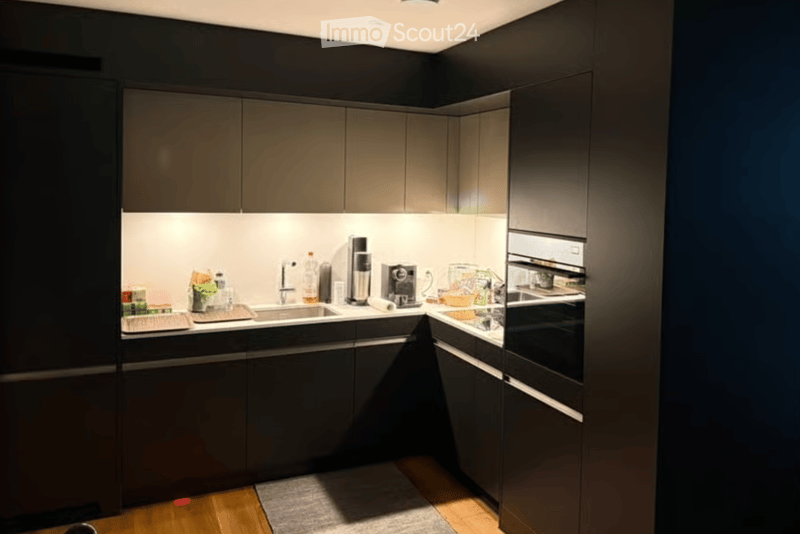 Modern kitchen with dark grey cabinets, stainless steel appliances, and a sleek design. Includes a sink, coffee maker, and oven.