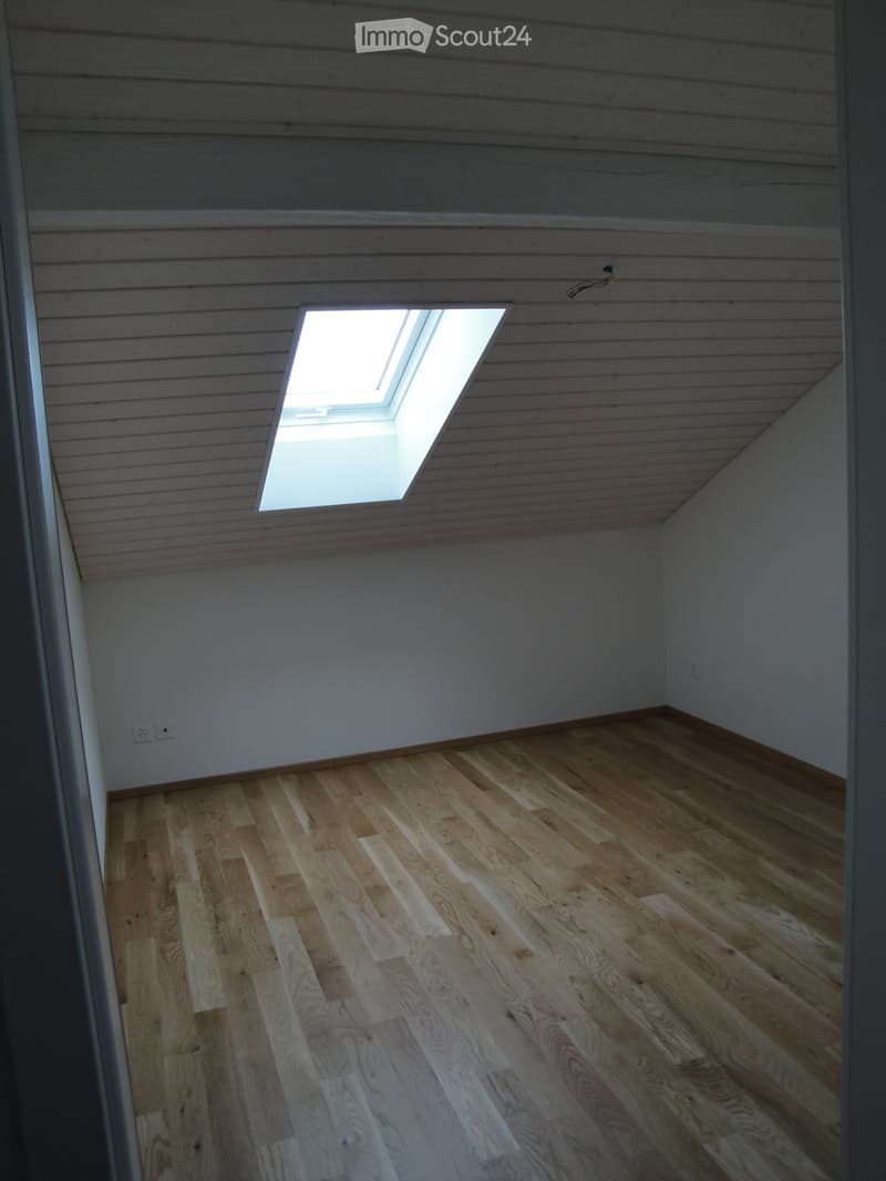 Empty room with wooden flooring and a skylight window in the ceiling.