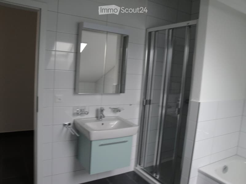 Modern bathroom with a white sink, mirror, and a light blue cabinet. Features a glass-enclosed shower area and a bathtub.