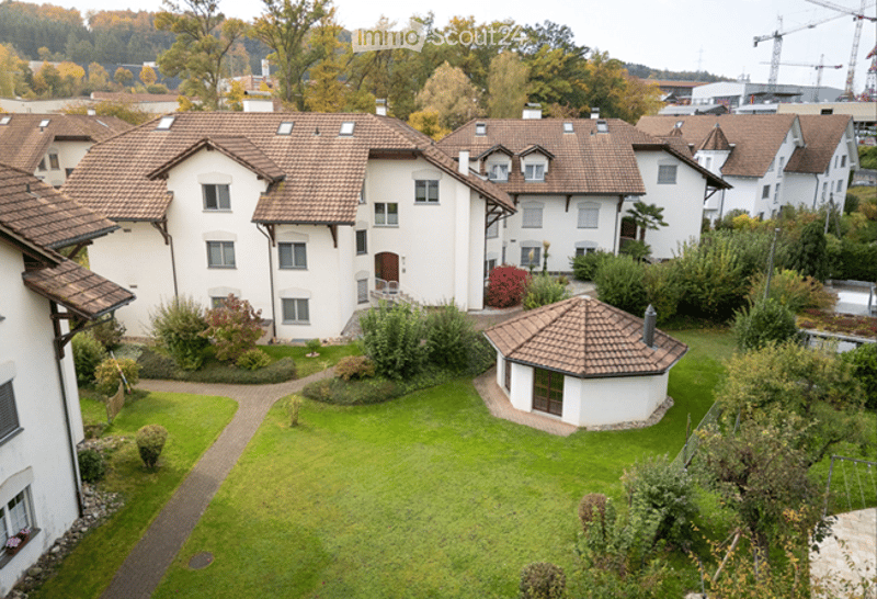 A multi-unit residential building complex with a central courtyard, surrounded by greenery and pathways.