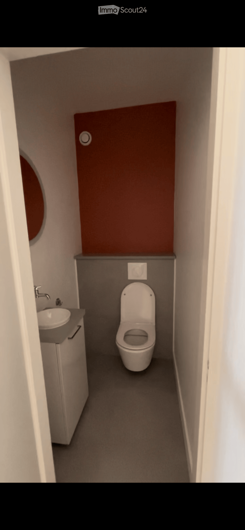 Modern compact bathroom with a toilet, sink, and faucet, featuring a dark grey wall and a brown accent wall.
