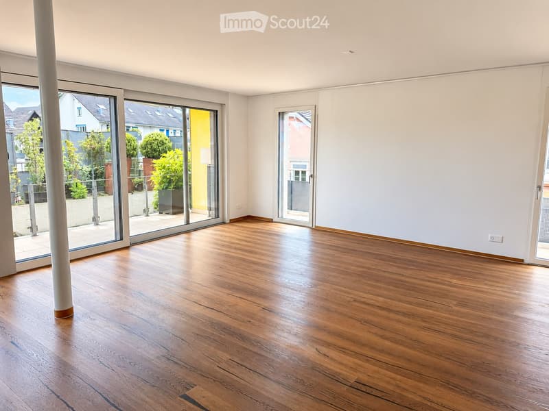 Empty room with wooden flooring, large sliding glass doors, and white walls.