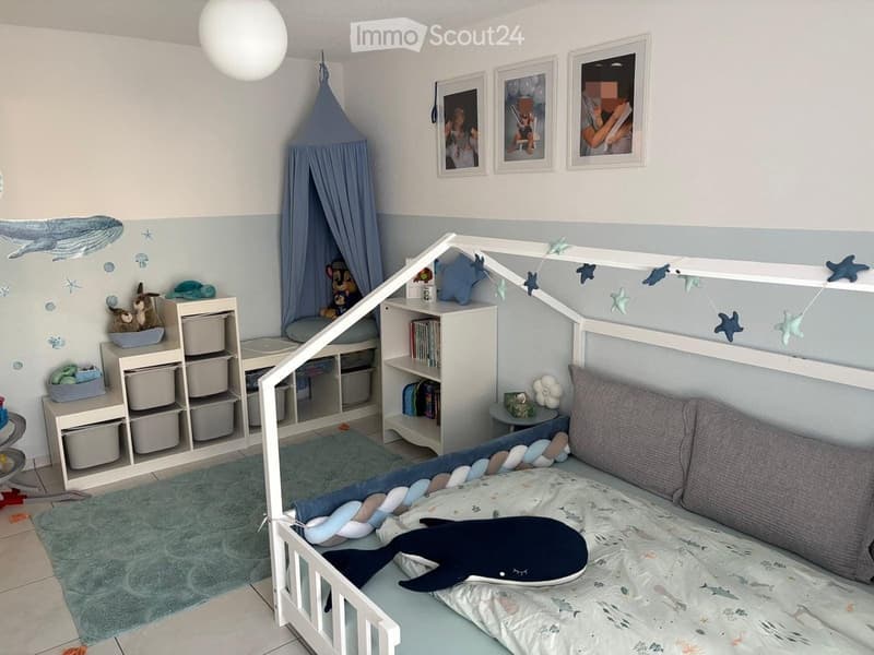A child's bedroom with a white bunk bed, ocean-themed decor, shelves with toys and books, and a small reading nook with a curtained tent.