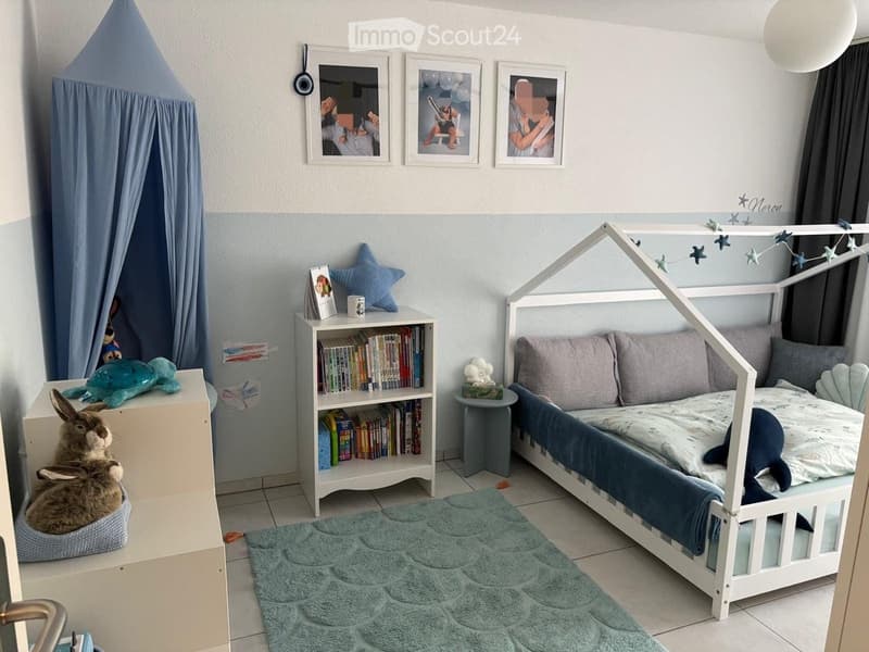 A child’s bedroom with a white bed, bookshelf, stuffed animals, and a play tent.