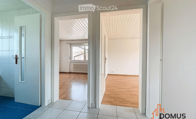 Empty hallway with wooden flooring, white walls, and multiple open doors leading to adjacent rooms.