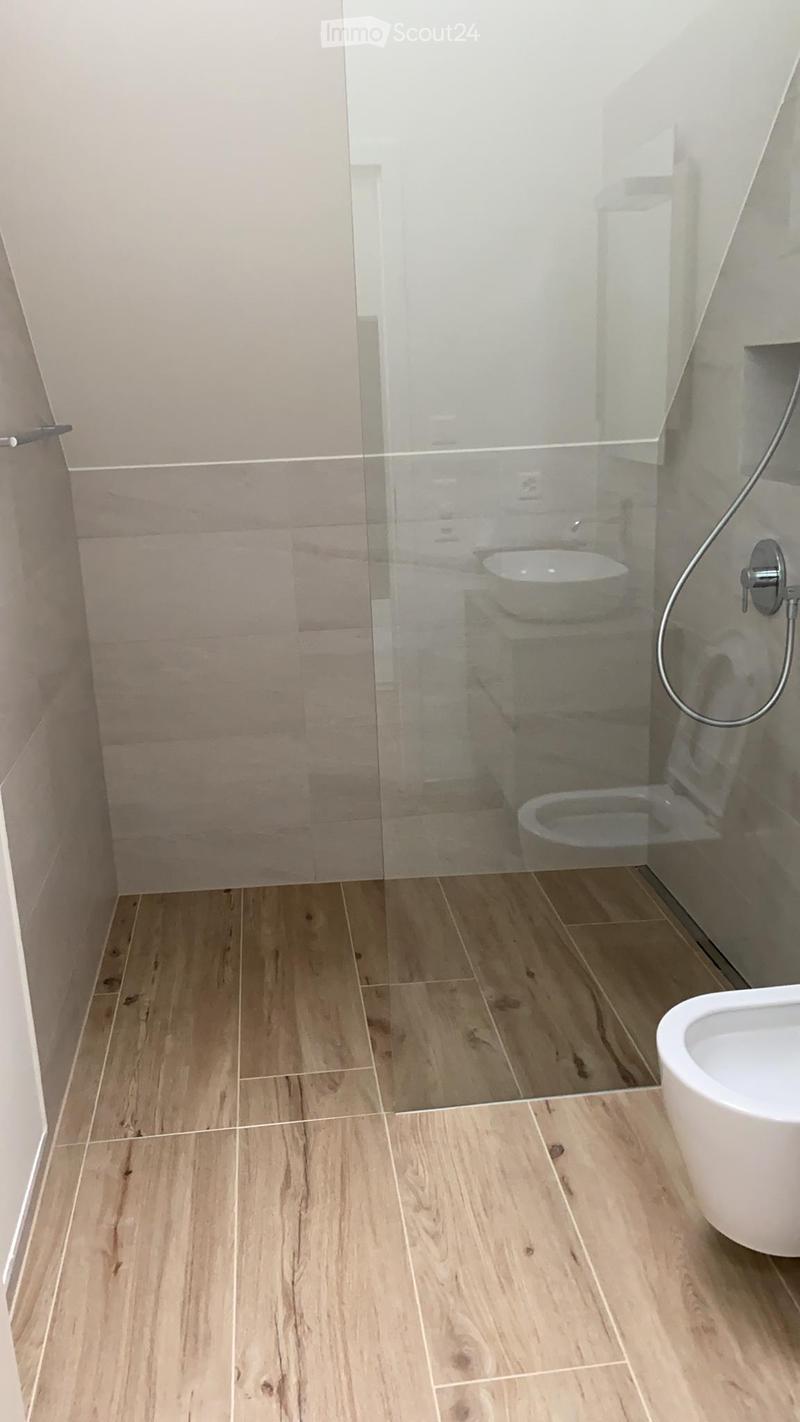 Bathroom with wooden flooring, glass shower enclosure, toilet, and modern fixtures.