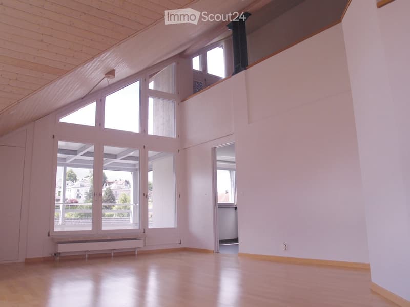 Bright, empty room with wooden flooring, white walls, large windows, and a radiator. No furniture or equipment present.