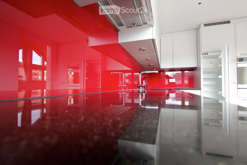 Modern kitchen with red walls, white cabinets, stainless steel sink, and a sleek countertop.