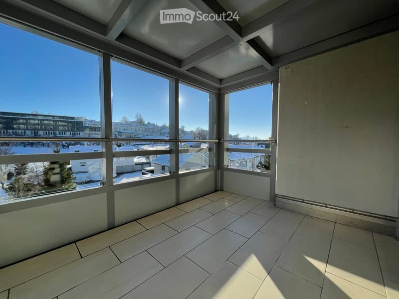 Empty balcony with large windows, tiled floor, and metal railing overlooking a snowy landscape.