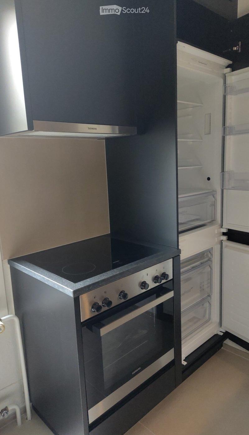 Modern kitchen with a built-in oven and refrigerator, both featuring sleek black and silver finishes.