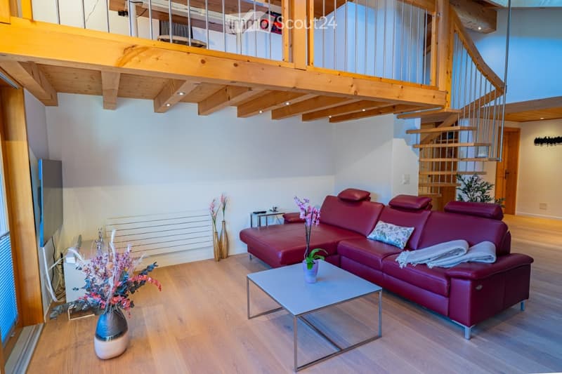 Modern living room with a red leather sofa, a white coffee table, and decorative vases. The room features wooden flooring and a staircase leading to an upper level.